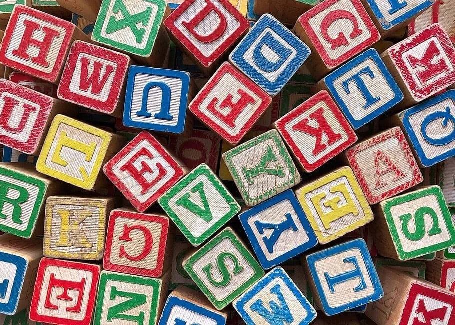 Colorful children's alphabet blocks with red, blue, green, and yellow letters scattered in a pile.